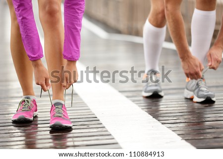 Runner feet. Running couple closeup of running shoes. Woman barefoot running shoes in foreground. Couple jogging on Brooklyn Bridge, New York.