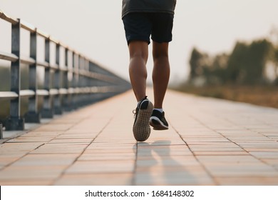 Runner feet running on road closeup on shoe. MAN fitness sunrise jog workout welness concept.
