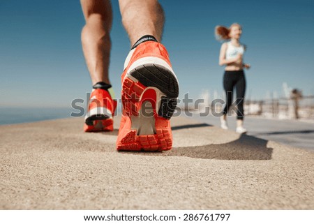 Runner feet running on road closeup on shoe. Sportsman fitness sunrise jog workout welness concept.