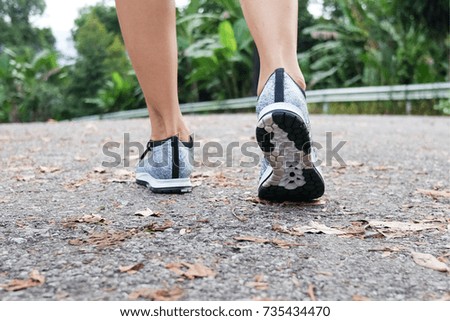Runner jogging beside garden road in the morning closeup on shoes