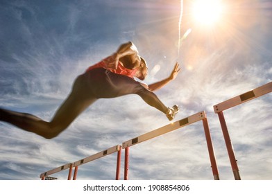 Runner jumping over running hurdle, low angle view