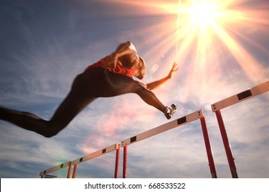 Runner jumping over running hurdle, low angle view - Shutterstock ID 668533522