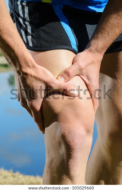 Runner leg injury grabbing knee. Quadriceps pain\
with caucasian male\
athlete.