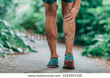 Runner leg injury painful leg. Man massaging sore calf muscles during running training outdoor from pain. Stock photo © 