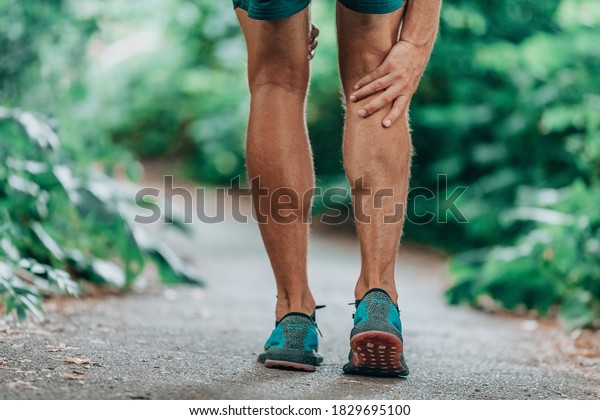 Runner leg injury\
painful leg. Man massaging sore calf muscles during running\
training outdoor from\
pain.