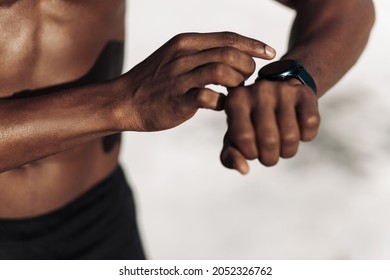 Runner looking at sports watch or wearable monitor with app, checking fitness or monitoring heart rate, sports and fitness outdoors outdoors in nature - Powered by Shutterstock