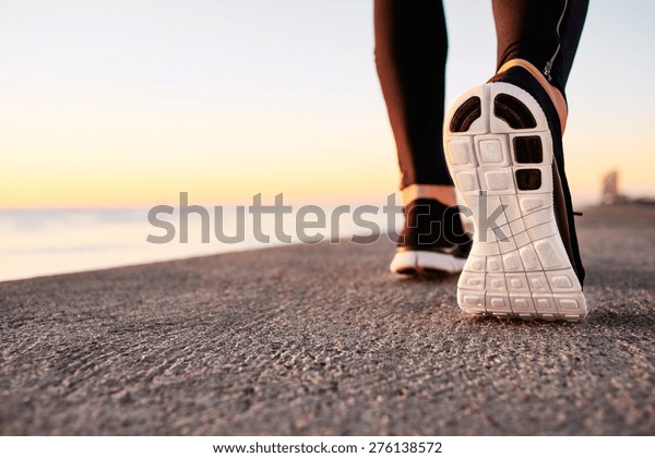Runner man feet running on road\
closeup on shoe. Male fitness athlete jogger workout in wellness\
concept at sunrise. Sports healthy lifestyle\
concept.\
