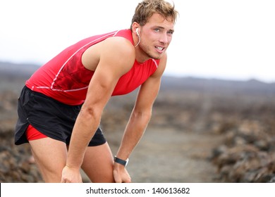 Runner man resting with music after running training for triathlon ironman on Hawaii. Male fitness model and triathlete relaxing looking with earphones listening to music. From Big Island, Hawaii, USA - Powered by Shutterstock