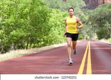 Runner Man Running On Road Training Sprint For Marathon Run. Sporty Fit Caucasian Male Fitness Sport Model Working Out Outside In Full Length.