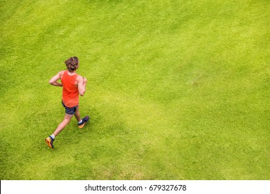 Runner Man Running On Summer Grass Park Jogging Healthy Lifestyle. People Working Out Cardio Top View. Copy Space On Green Texture Background.