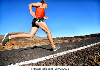 Runner man running sprinting for success on run. Male athlete runner training at fast speed. Muscular fit sport model sprinter exercising sprint on mountain road. Full body length of Caucasian model.