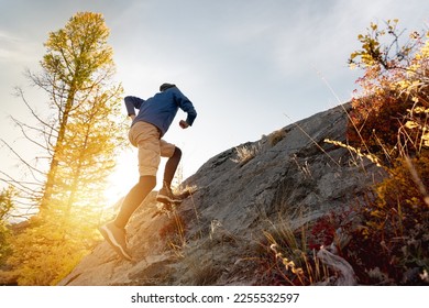 Runner man runs uphill crosscountry in sunset forest and mountains