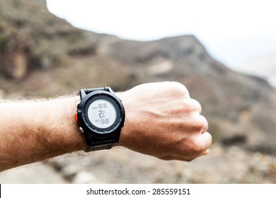Runner on mountain trail looking at wearable sports watch, checking GPS position, performance or heart rate pulse and training working out. Healthy lifestyle, sport and fitness outdoors in nature.