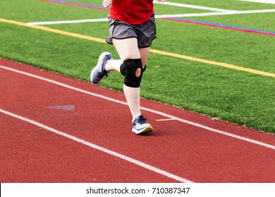 A Runner Is Practicing On A Red Track While Wearing A Large Black Knee Brace.