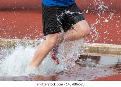 Runner Running Through The Steeple Chase Water Bake On A Running Track
