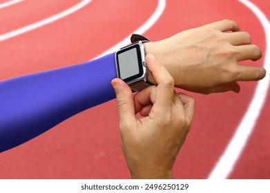 Runner setting her smart watch monitor before running on track in the stadium