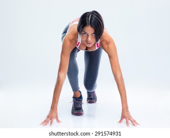 Runner Sporty Woman In Start Position Over Gray Background. Looking At Camera