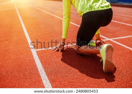 A runner is in the starting position, getting ready for a sprint race on a track at sunrise, full of determination