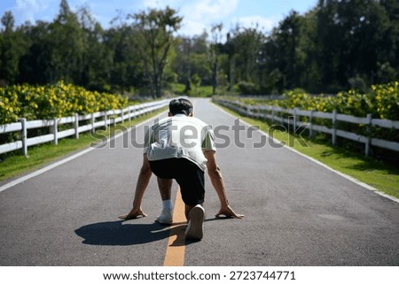 Runner in starting position on an empty road, symbolizing a fresh start, motivation, and determination for new year fitness goals..