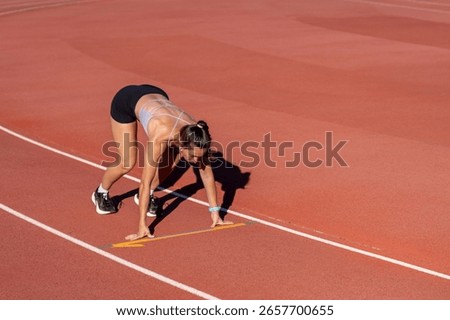 Runner in starting position on track, ready for sprint, embodying determination and athleticism