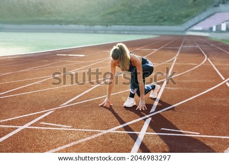 Runner taking off from the starting blocks on running track. Jogger activity. Female athlete. Sportswoman. Female athlete starting her sprint on a running track. Cardio exercises. Workout concept