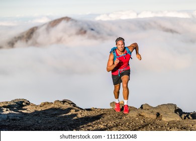 Runner trail running fitness man on endurance run - motivation and concentration on race in sky and clouds background on nature landscape. Focused athlete with backpack and hairband training cardio. - Shutterstock ID 1111220048
