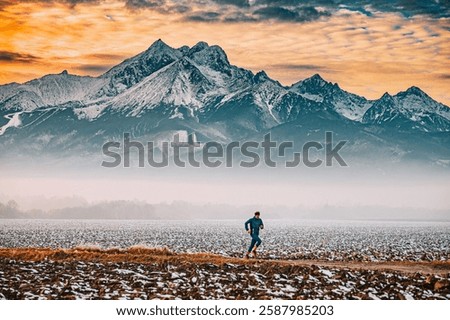 Runner train in the fields during winter season, Massive mountains in background. Orange sunset light