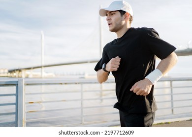 A Runner Training Runs In Sports Clothes, A Man Fitness Watch On His Arm To Measure The Result