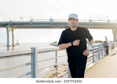 A Runner Training Runs In Sports Clothes, A Man Fitness Watch On His Arm To Measure The Result