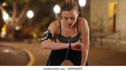 Runner Using Smartwatch Fitness Tracker While Running At Night In Urban Park