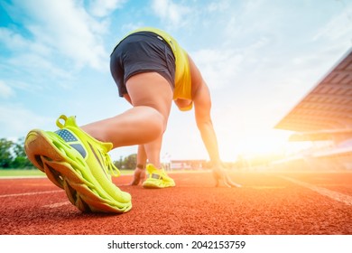 Runner Using Starting Block To Start His Run On Race Track. Athlete Runner Feet Running On The Racetrack.  Young Man Jogging In Track Stadium.