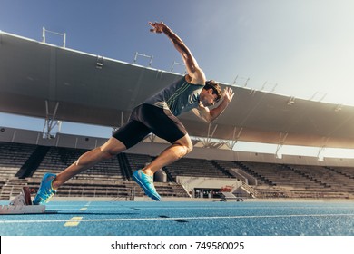 Runner using starting block to start his run on running track in a stadium. Athlete starting his sprint on an all-weather running track. - Shutterstock ID 749580025