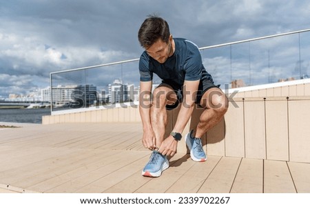 A runner wears running shoes, a man training uses a fitness watch on his arm.