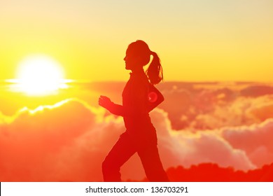 Runner woman running in sunshine sunset. Fitness athlete training trail running marathon in mountains above the clouds in beautiful mountain landscape. Female in jogging in silhouette. - Powered by Shutterstock