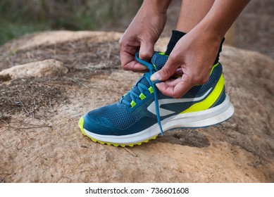 Runner woman tying laces of running shoes preparing for park jogging. Closeup of hands lacing cross training sneakers trainers for cardio workout. Female athlete living a fit and active life. - Powered by Shutterstock