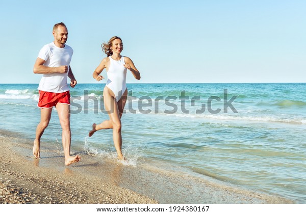 Runners fitness\
couple running training on beach. Cardio workout people doing\
exercise. Active sports\
lifestyle.