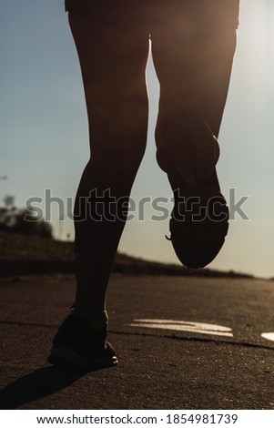 Runner's foot running on the road - Silhouette of legs and feet of women fitness training at sunset.