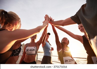Runners high fiving each other after a good training session. Group of athletes give each other high five after race.