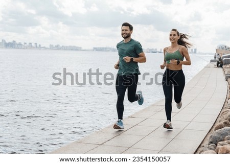 Runners partners training in sports clothes and running shoes.  Athletes exercise for health. Happy young people jogging together. Use a fitness watch and a cardio app.
