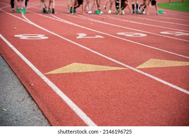 Runners Are Ready For The Starting Gun At Their Starting Blocks. High Energy Closeup Of Athletic Lane Markings And Numbers Shot Outdoors In Natural Light With Copy Space Athletic Background.