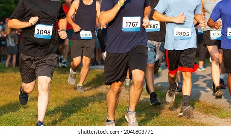 Runners running a 5K race on grass in during a very crowded event.