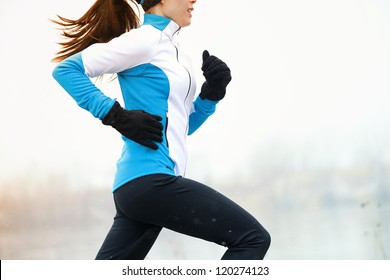 Running Athlete Woman Sprinting During Winter Training Outside In Cold Snow Weather. Close Up Showing Speed And Movement.