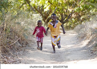 Running Black African Ethnicity Boys Having Fun Smiling And Laughing In Typical African Village Town