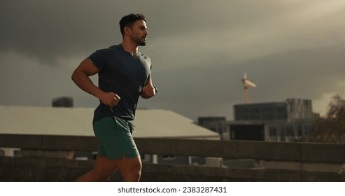 Running, city or man with workout in training, cardio jog or fitness for marathon competition. athlete, wellness or strong body for france with progress, road or health lifestyle and overcast sky - Powered by Shutterstock