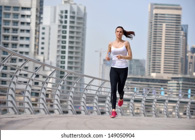 Running In City Park. Woman Runner Outside Jogging At Morning With Dubai Urban Scene In Background