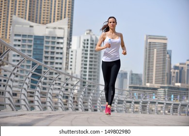 Running In City Park. Woman Runner Outside Jogging At Morning With Dubai Urban Scene In Background