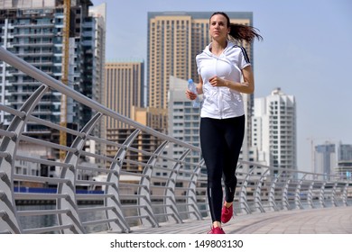 Running In City Park. Woman Runner Outside Jogging At Morning With Dubai Urban Scene In Background