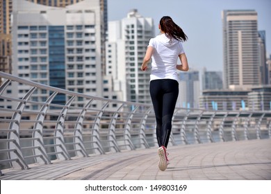 Running In City Park. Woman Runner Outside Jogging At Morning With Dubai Urban Scene In Background