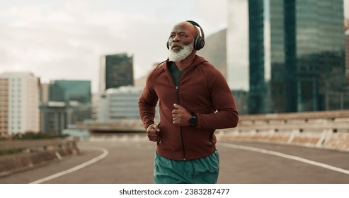 Running, city and senior man with headphones in training, streaming music and fitness. Retirement, black person or wellness of african runner for race in progress, urban road or marathon competition - Powered by Shutterstock