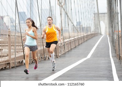 Running Couple. Runners Training Outside. Asian Woman And Caucasian Man Runner And Fitness Sport Models Jogging In Full Body Showing Brooklyn Bridge, New York City, USA.